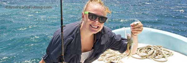 girl holding a small fish on a boat with fishing line